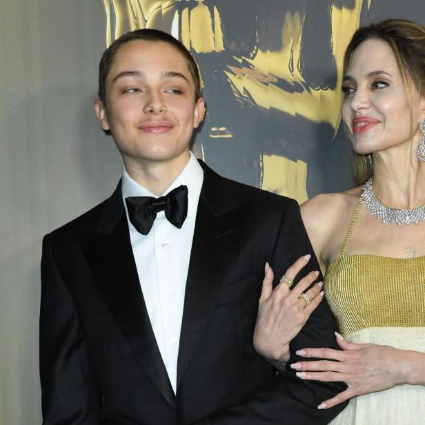 Angelina Jolie, mit Schmuck und goldenem Kleid, posiert mit Sohn Knox im Smoking.