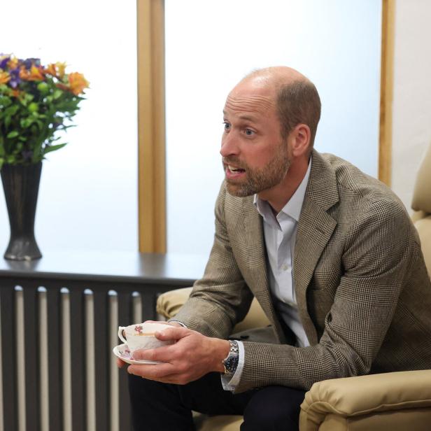 William im Sessel hält eine Teetasse in der Hand, neben ihm steht eine Blumenvase.