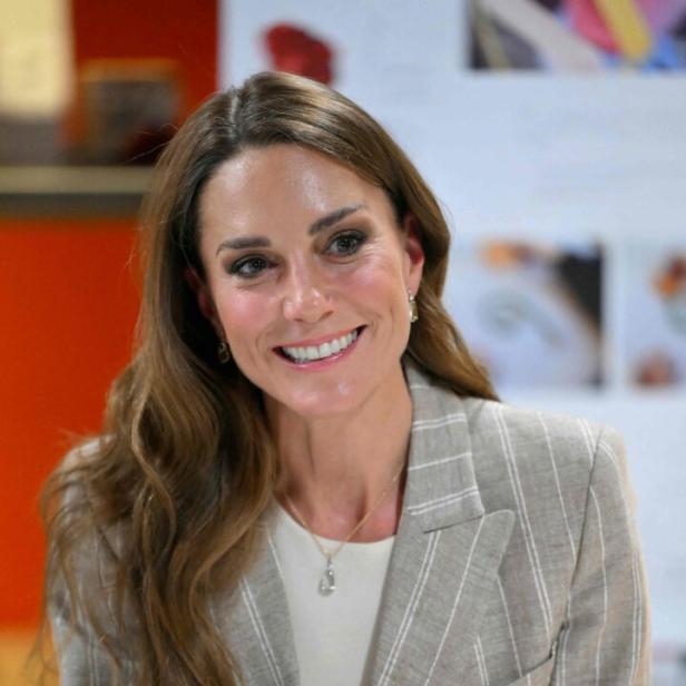 Prinzessin Kate lächelt in einem gestreiften Blazer und mit verschränkten Händen.