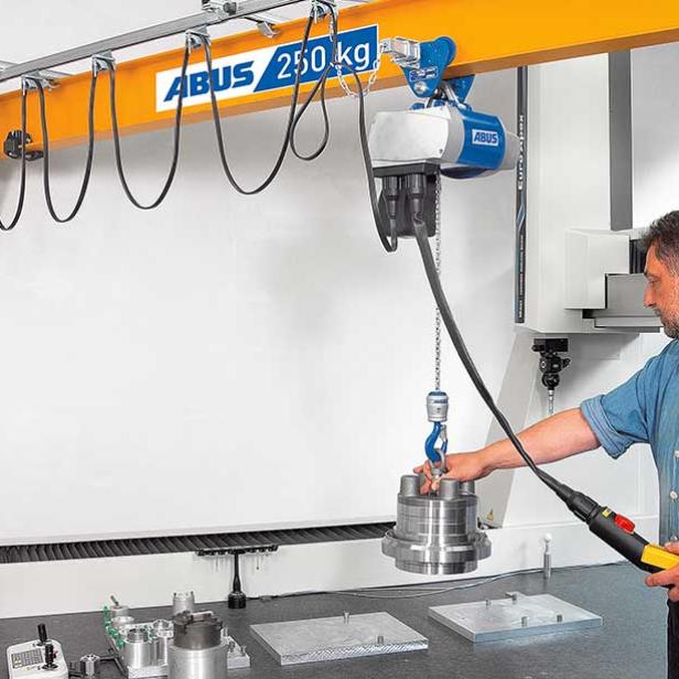 Mitarbeiter bedient einen ABUS-Schwenkkran und hebt ein Metallteil in einer Werkstatt.