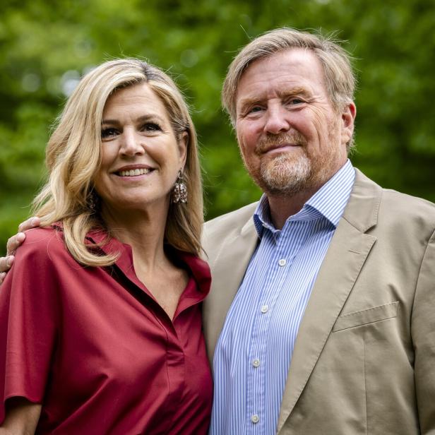König Willem-Alexander und Königin Máxima lächeln vor grünem Hintergrund.
