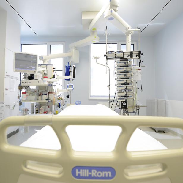 Krankenhauszimmer mit leerem Bett, medizinischen Geräten, Monitoren und Infusionspumpen in heller Umgebung.