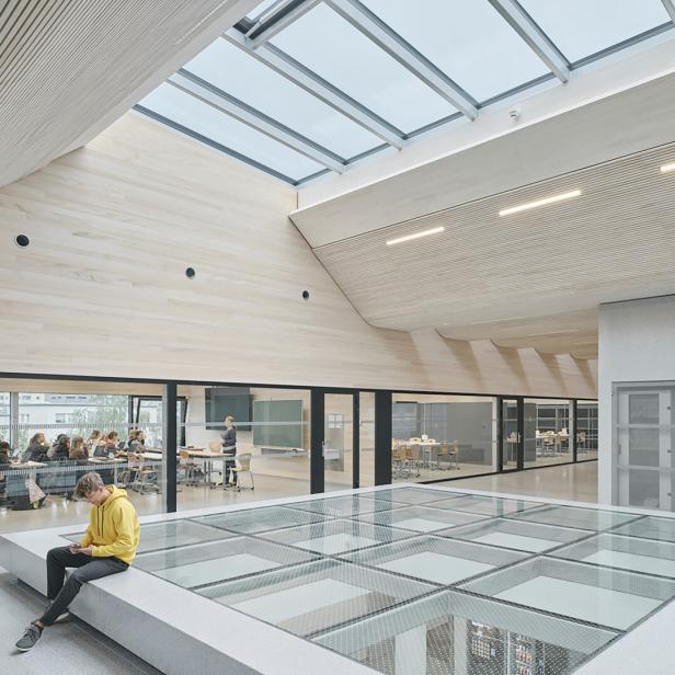 Innenaufnahme der TU Bau und Design in Innsbruck. Viel Holz und Glas zeichnen das Gebäude aus. 