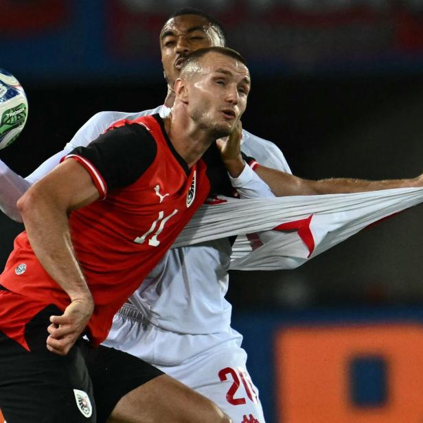 Zwei Fußballspieler kämpfen um den Ball, einer zieht am Trikot des anderen.