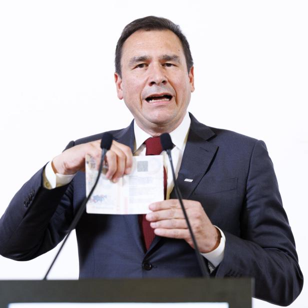 Ein Mann im Anzug spricht an einem Rednerpult und hält ein aufgeschlagenes Dokument in den Händen.