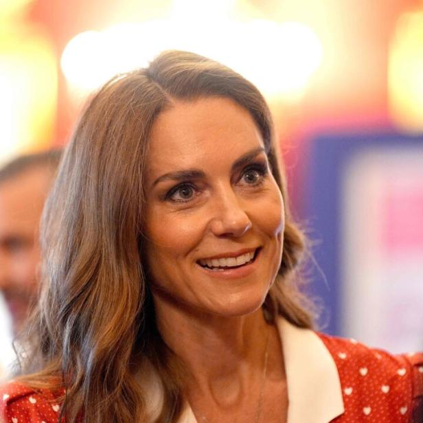 Prinzessin Kate blickt zur Seite. Sie trägt ein rotes Kleid mit weißen Punkten.