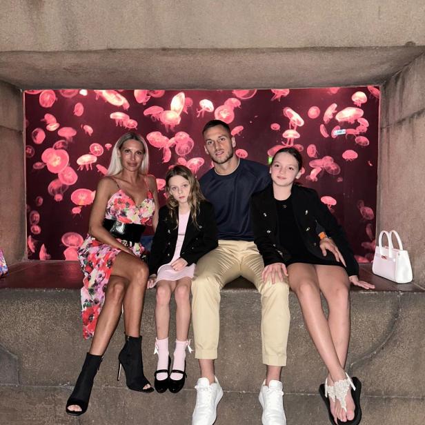 Marko Arnautovic sitzt mit Partnerin Sarah und den beiden Töchtern Alicia und Emilia vor einem Aquarium mit Quallen.