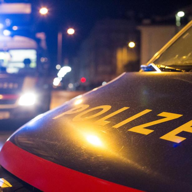 Zwei Polizeifahrzeuge stehen nachts mit eingeschaltetem Blaulicht auf einer Straße.
