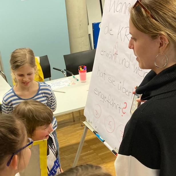 Kinder diskutieren mit einer Pädagogin vor einem Flipchart über Kinderrechte und Beteiligung.