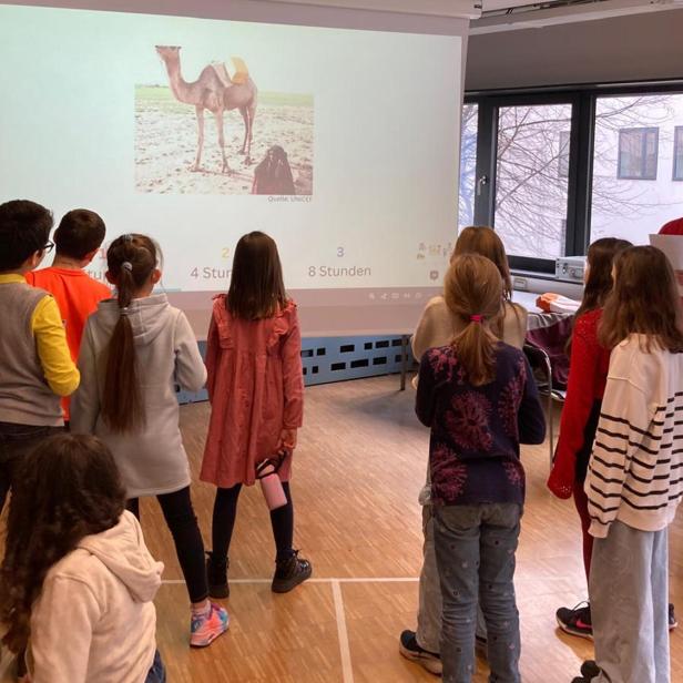 Kinder verfolgen eine Präsentation und diskutieren gemeinsam im Unterricht.
