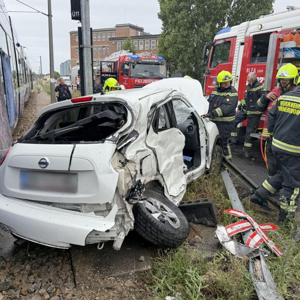 Das Wrack eines weißen Auto neben Feuerwehrmännern