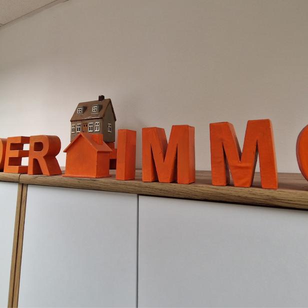 Schriftzug von Manseder Immobilien mit Hausmodellen im Unternehmensbüro.