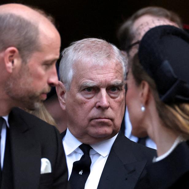 Ex-Prinz Andrew steht zwischen Prinz William und Catherine, Prinzessin von Wales, bei einer offiziellen Veranstaltung in dunkler Kleidung.