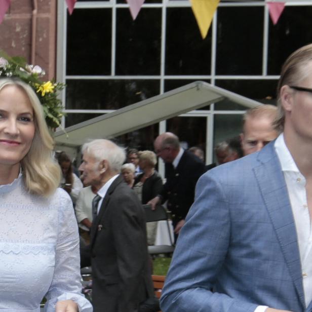 Kronprinzessin Mette-Marit von Norwegen mit Blumenkranz und Marius Borg Høiby in einem hellblauen Sakko bei einer Veranstaltung im Freien.