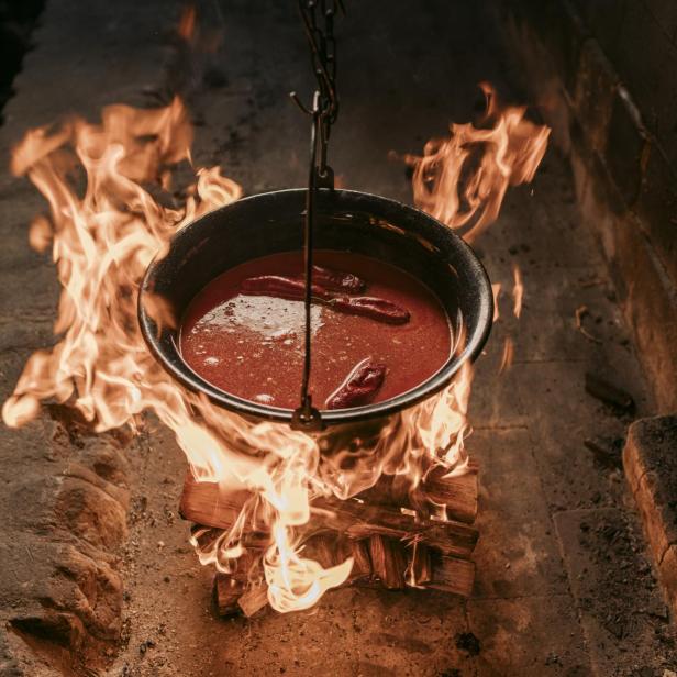 Ein traditioneller kroatischer Eintopf wird über offenem Feuer in einem Kessel zubereitet, wie es Gastgeber im Rahmen der „Local Host“-Initiative anbieten.
