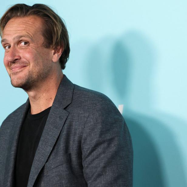 Jason Segel lächelt vor einem hellblauen Hintergrund in die Kamera.