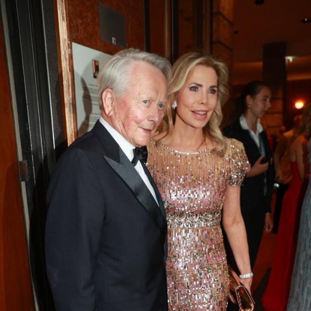 Wolfgang Porsche im Smoking und Gabriele Porsche in einem glitzernden Abendkleid stehen nebeneinander bei einer festlichen Veranstaltung.