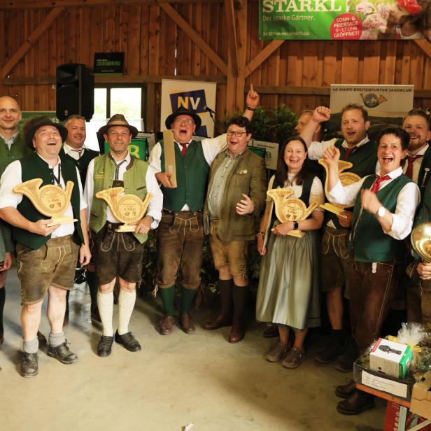 Eine Gruppe in Tracht feiert bei einer Veranstaltung des Breitenfurter Jagdklubs mit Trophäen in einer Holzhalle.