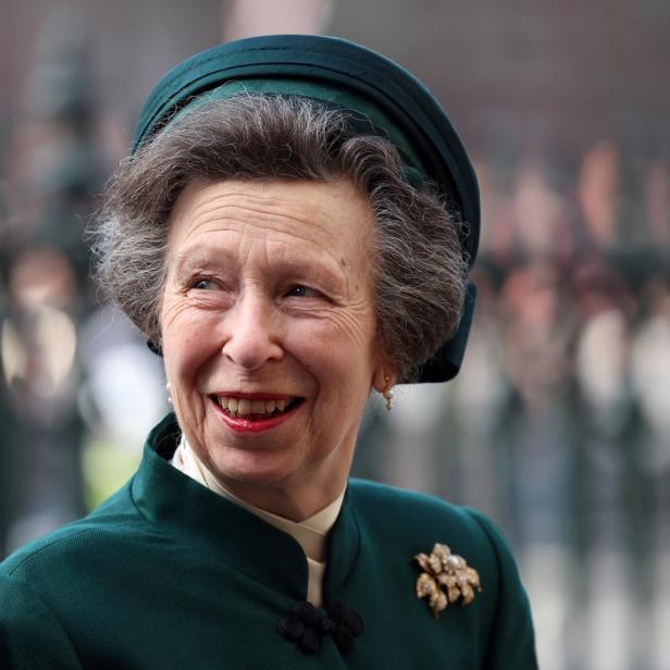 Prinzessin Anne lächelt in einem dunkelgrünen Kostüm mit passendem Hut und einer auffälligen Brosche.