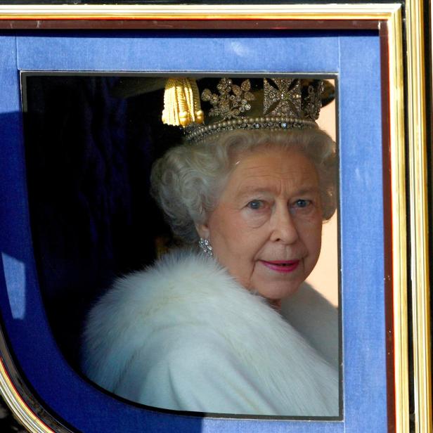 Queen Elizabeth mit einer Krone auf dem Kopf blickt durch das Fenster einer Kutsche