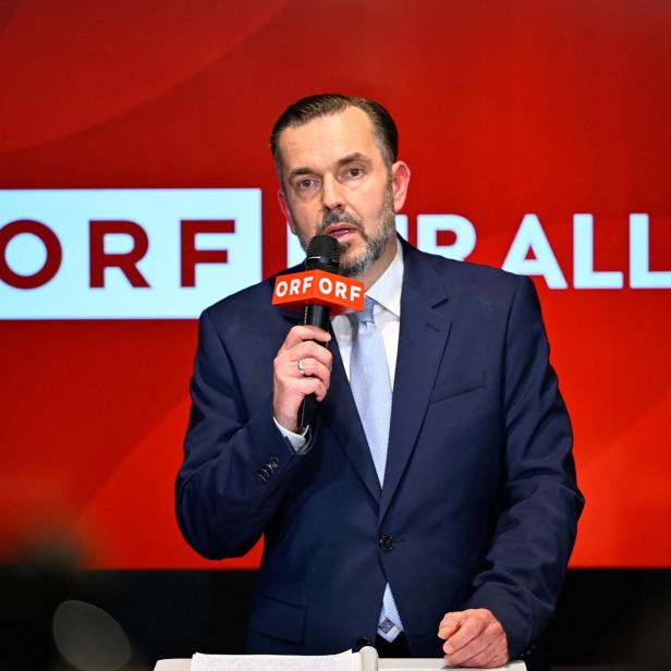 Ein Mann im Anzug spricht vor einem roten Hintergrund mit dem Schriftzug „ORF für alle“ in ein Mikrofon mit ORF-Logo.