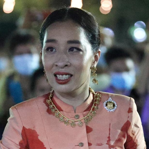 Prinzessin Bajrakitiyabha von Thailand trägt ein pfirsichfarbenes Kleid mit roten Mustern und eine goldene Halskette.