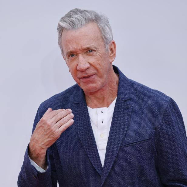 Schauspieler Tim Allen trägt ein weißes Hemd unter einem dunkelblauen Sakko vor einem hellen Hintergrund.