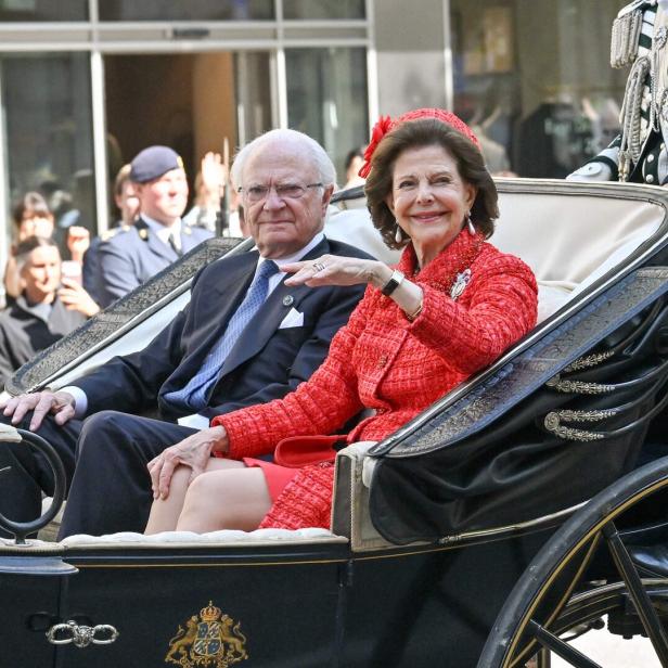 König Carl XVI. Gustaf und Königin Silvia von Schweden fahren in einer Kutsche an Schaulustigen vorbei.