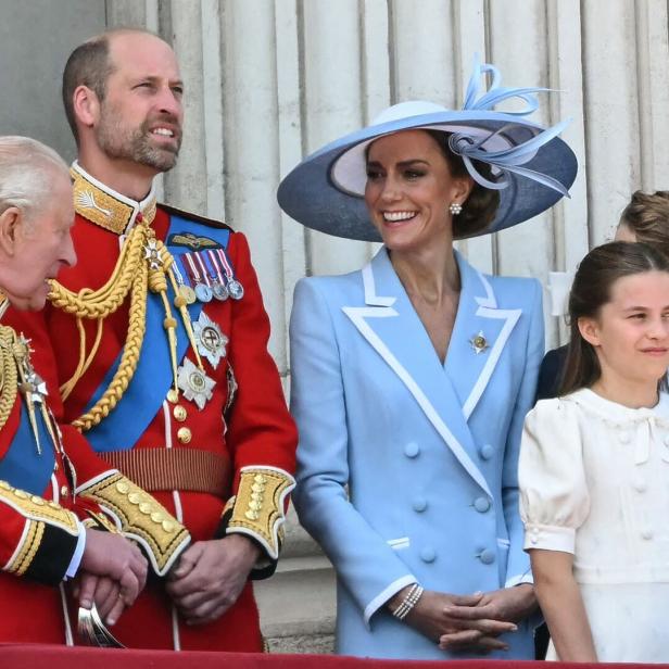 König Charles III., Prinz William, Prinzessin Kate und Prinzessin Charlotte stehen gemeinsam auf einem Balkon.
