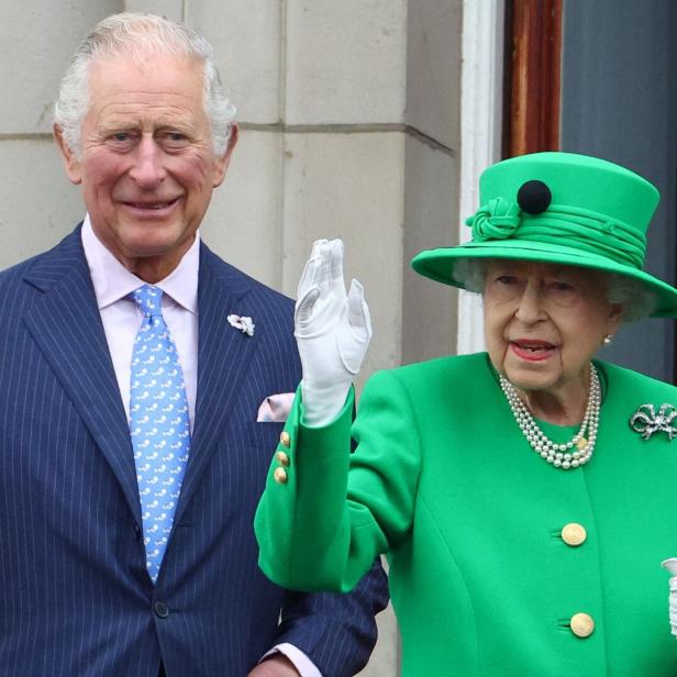 Charles steht neben Queen Elizabeth II., die in einem grünen Kostüm winkt.
