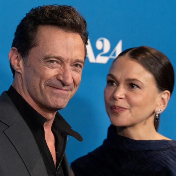 Hugh Jackman und Sutton Foster posieren gemeinsam vor einem blauen A24-Hintergrund.