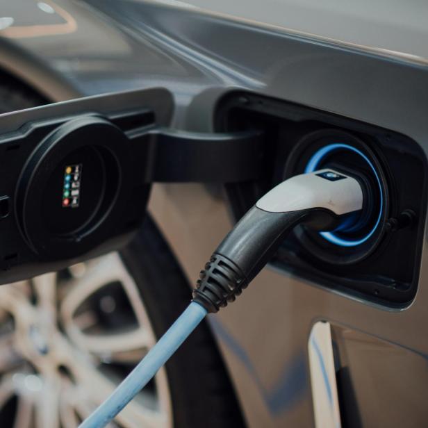 Nahaufnahme eines Elektroautos beim Ladevorgang mit eingestecktem Ladestecker