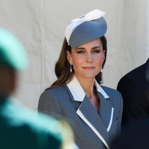 Catherine, Prinzessin von Wales, trägt einen grauen Blazer mit weißem Revers und einen passenden Hut.
