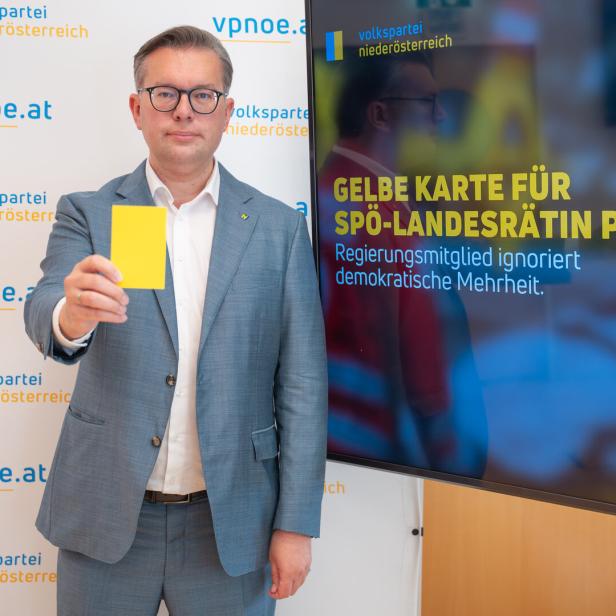 Mann im Anzug hält eine gelbe Karte; daneben steht auf einem Monitor: „Gelbe Karte für SPÖ-Landesrätin Prischl“.