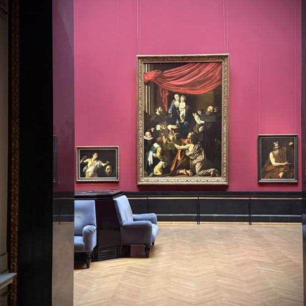 Neu gestalteter Saal der KHM-Gemäldegalerie mit dunkelrosa Wänden, einem großen barocken Gemälde und zwei kleineren Werken.