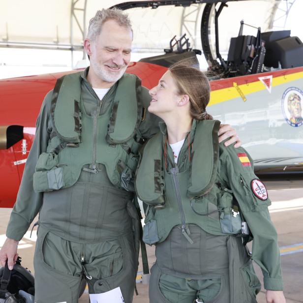 König Felipe VI. von Spanien steht in Fliegerkombi neben seiner Tochter Prinzessin Leonor vor einem Trainingsflugzeug.