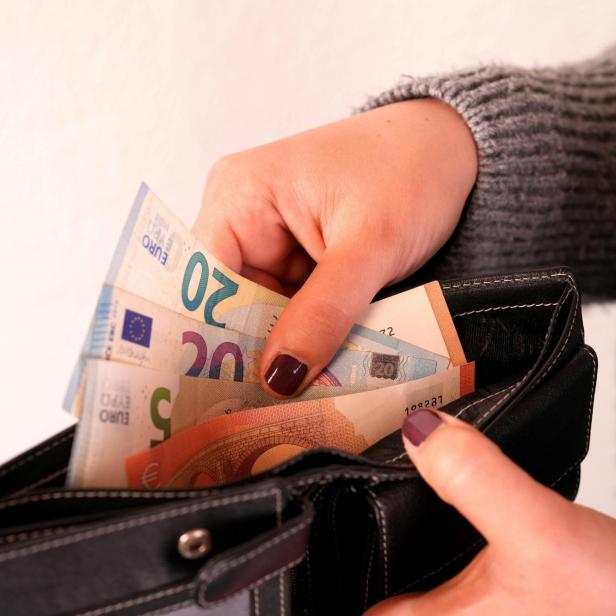 Eine Frau, die Gelscheine in ihre Börse steckt.
