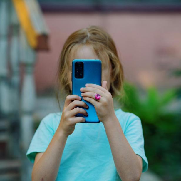 Mädchen hält Handy vors Gesicht