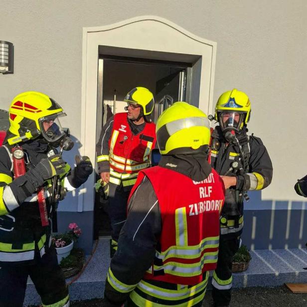 Feuerwehrleute in Atemschutz vor einem Haus nach dem Brand.