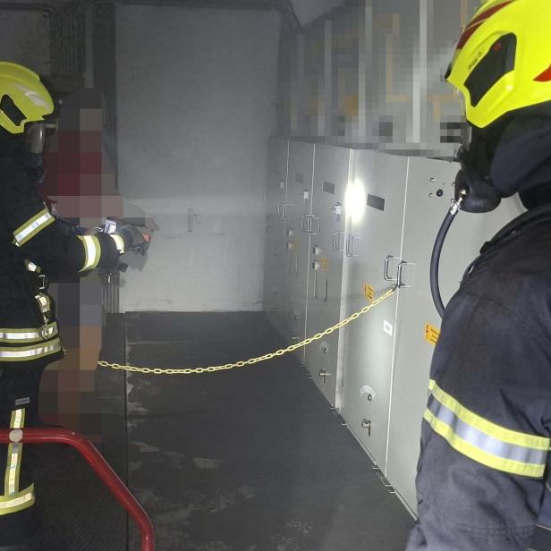 Feuerwehrleute in Atemschutz kontrollieren einen verrauchten Schaltraum.