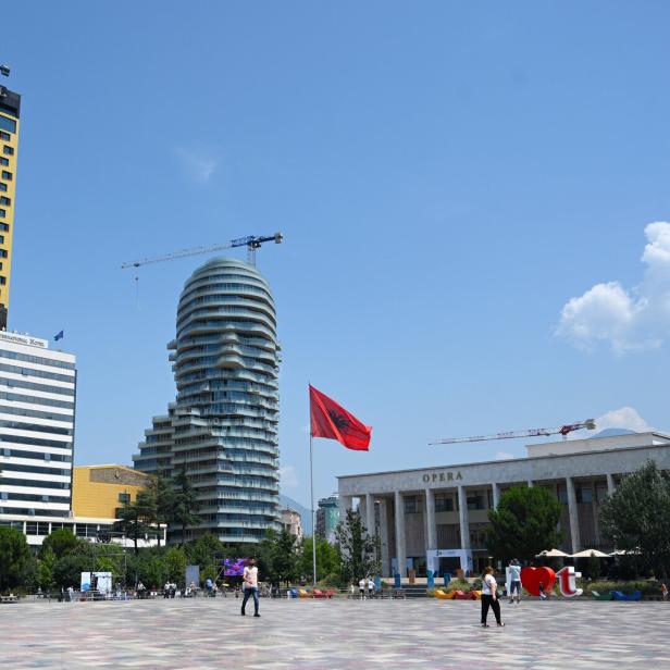 Der Skanderbeg-Platz in Tirana mit dem InterContinental Hotel, dem markanten Eye of Tirana Hochhaus und der albanischen Flagge vor der Oper.