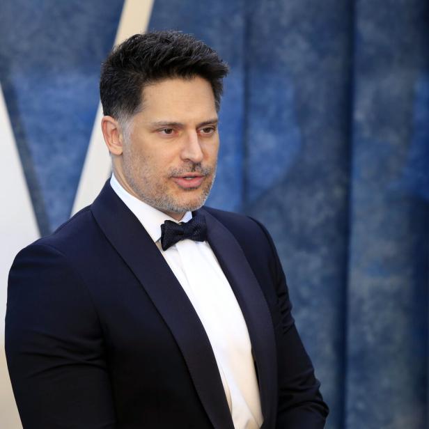 Joe Manganiello trägt einen dunklen Smoking mit Fliege vor einem blauen Hintergrund.