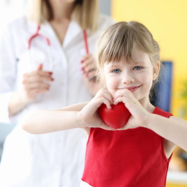 Little girl showing heart with hands in doctors office