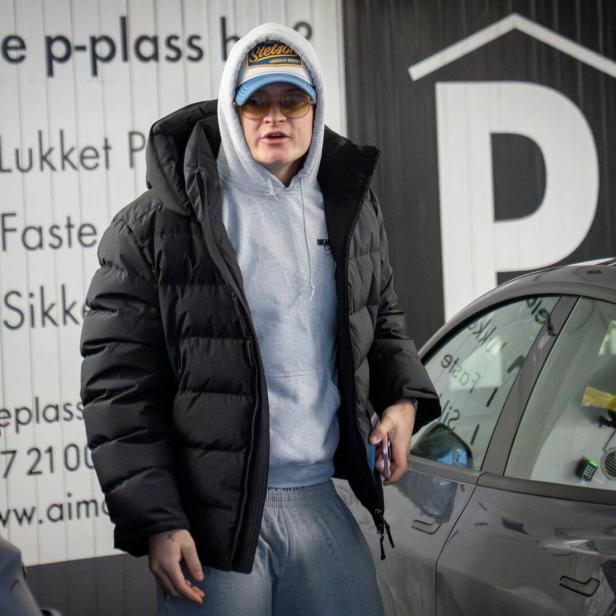 Marius Borg Høiby mit Kapuzenpullover, schwarzer Daunenjacke, Sonnenbrille und Stetson-Cap steht vor einem Parkhaus.