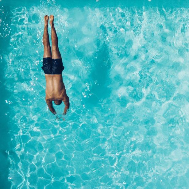 Mann springt kopfüber in einen Pool.