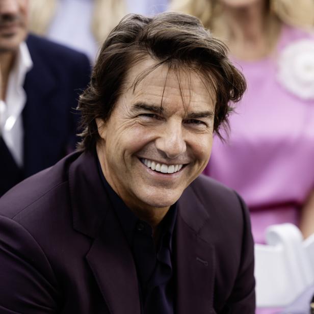 Tom Cruise lächelt in die Kamera, während er ein dunkles Sakko trägt.