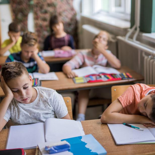 Erschöpfte Kinder sitzten in einem Klassenzimmer.