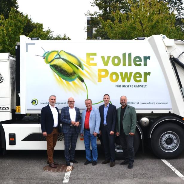 Fünf Männer stehen vor einem Müllwagen mit der Aufschrift „E voller Power“ und einem Käfermotiv.