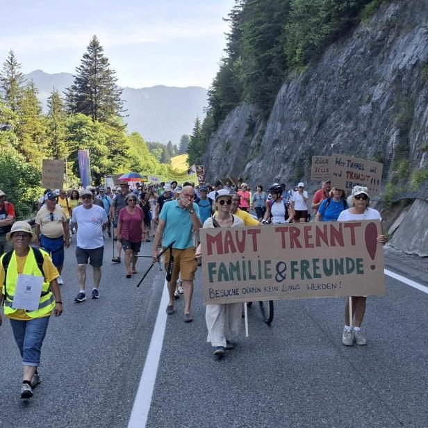 Demonstranten marschieren auf der Fernpassstraße bei Tirol mit Transparenten gegen das Fernpasspaket.
