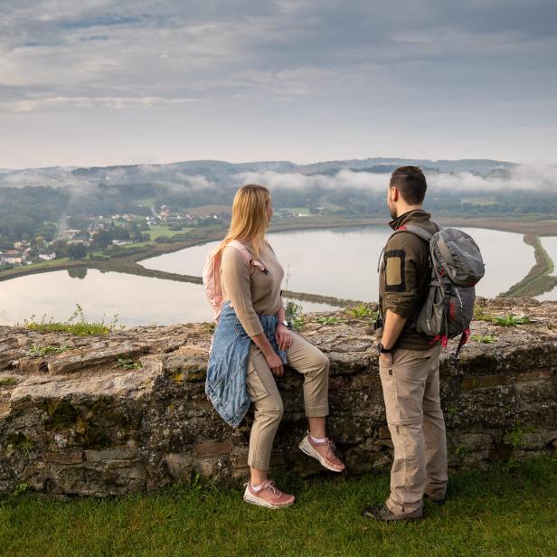 Zwei Personen stehen vor einer Steinmauer